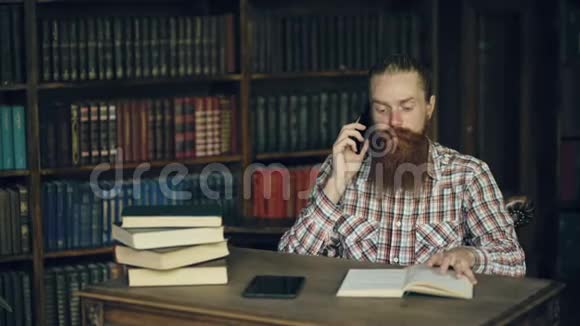 在大学图书馆准备考试的时候留胡子的学生在打电话视频的预览图