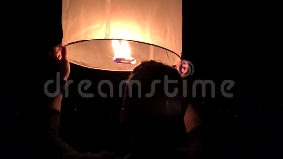 年轻夫妇发射了一个红色的中国天空飞火灯笼在海滩上做一个Wiss高清慢镜头泰国普吉岛视频的预览图