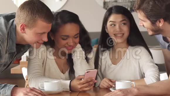 四个朋友在咖啡厅看智能手机视频的预览图