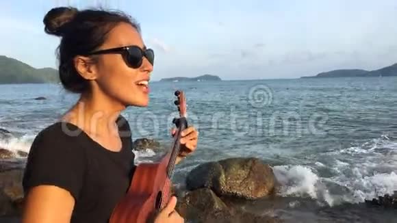 可爱的白种人女孩在海滩上演奏四弦琴和唱歌高清泰国普吉岛视频的预览图