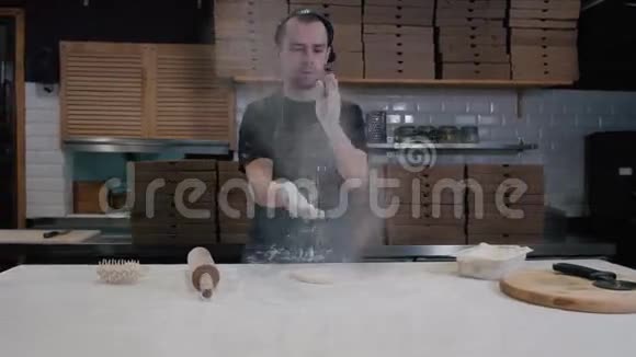 面包师用擀面杖把面团摊开拍拍手年轻的厨师做披萨送外卖视频的预览图