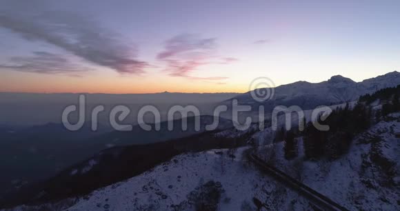 前方空中俯瞰冬雪山路蓝色小时黄昏或黎明黄昏阿尔卑斯山街道雪路视频的预览图
