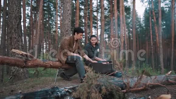 一对坐在森林里的森林里烧烤的情侣男朋友进来视频的预览图