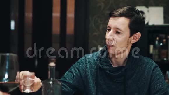 年轻的亚盲人喝着和朋友一起在餐桌上喝的伏特加视频的预览图