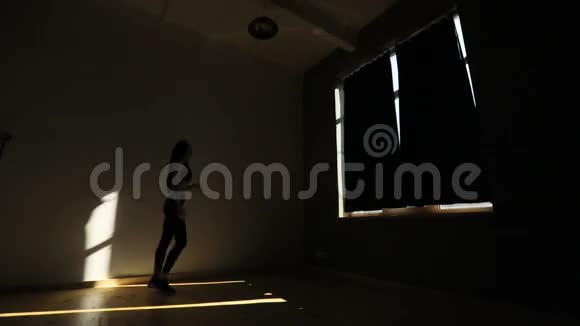 这位运动女子在黑暗的工作室里抬脚做弓步的水平视野视频的预览图