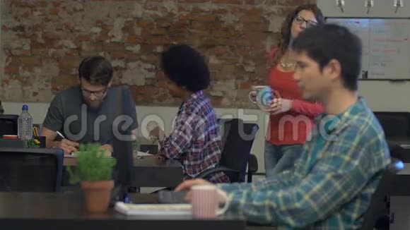 工作的人在办公室里喝着咖啡谈论着看电脑屏幕视频的预览图