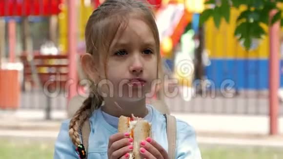 漂亮的年轻女孩在公园里吃热狗视频的预览图