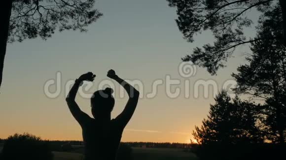 日落后年轻快乐的女人在森林里跳舞和玩视频的预览图