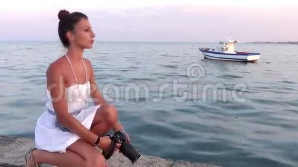 年轻的摄影师蓝色的大海和背景上的小船视频的预览图