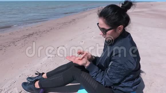 在刮风的日子里女人坐在海边的沙滩上分拣琥珀碎片视频的预览图