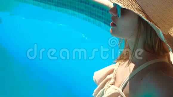 一个戴着帽子和眼镜的年轻女孩站在游泳池水里穿着泳衣视频的预览图