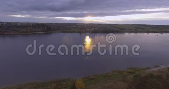 飞越落日河俯瞰岸边的一个小村庄视频的预览图