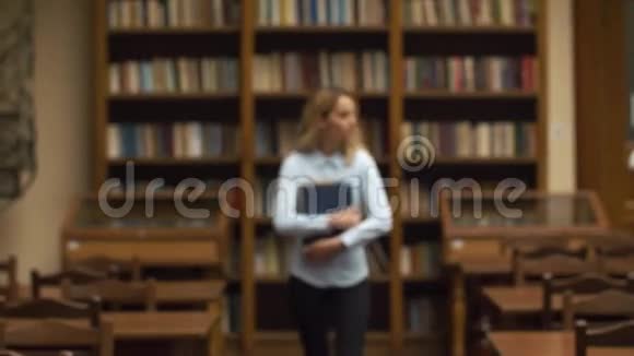 学生拿着大书在图书馆散步视频的预览图