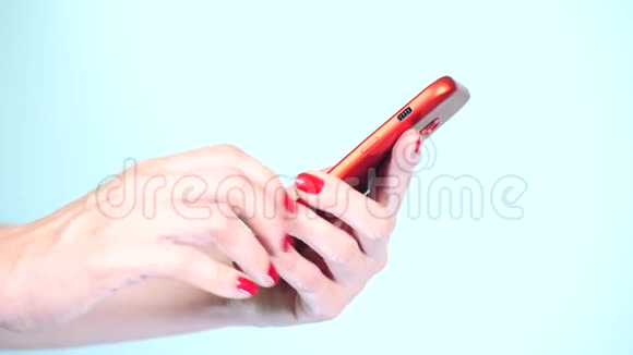 特写红色美甲的女性手在彩色背景上使用智能手机4k慢镜头拍摄视频的预览图
