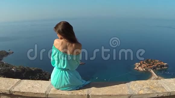 美丽的黑发女孩健康的长发放松在岛上的岩石上的海洋和蓝天斯特凡视频的预览图