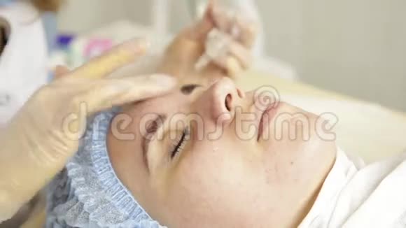 美丽的女人在水疗沙龙接受美容治疗美容医生戴着医用手套摸着女孩脸视频的预览图