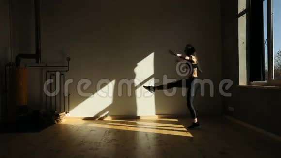 那个女人在灯光昏暗的工作室里工作和跳跃的景象视频的预览图