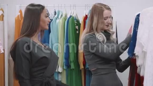 可爱的微笑的年轻女子和朋友在服装店挑选晚礼服视频的预览图