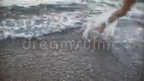 男人晒黑的腿在沙滩上奔跑海上行走的人视频的预览图