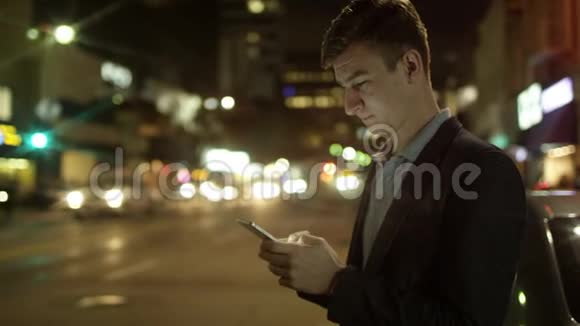 年轻男性晚上站在街上发短信视频的预览图