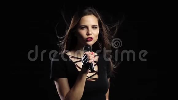 歌手唱着充满活力的歌她的头发在风中飘扬黑色背景慢动作视频的预览图