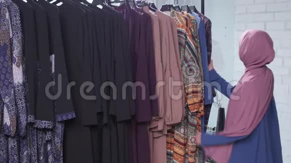 一位年轻的穆斯林妇女在商店里挑选衣服视频的预览图