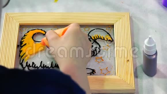 这位年轻艺术家的手在玻璃上用黄色颜料作画视频的预览图