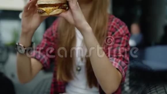 一个女孩在街城咖啡馆享用新鲜汉堡的特写镜头视频的预览图