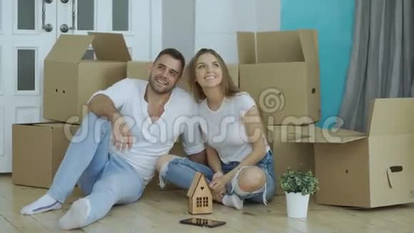 幸福的夫妇坐在新房子的地板上年轻人给女朋友钥匙吻她视频的预览图
