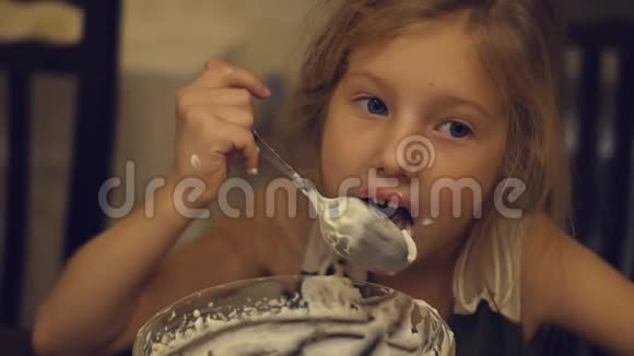 一个迷人的小女孩在做蛋糕后贪婪地吃厨房里剩下的奶油视频的预览图