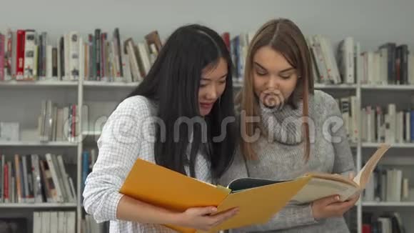 两个女学生比较图书馆两本书中的信息视频的预览图