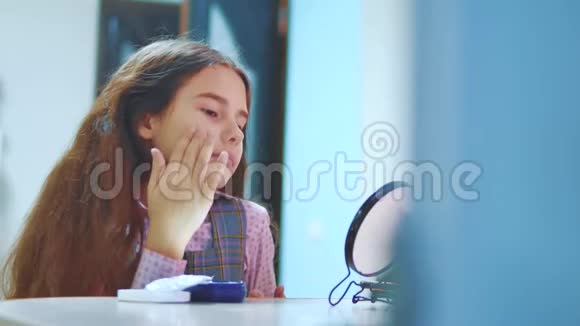 可爱的黑发西班牙小女孩在她的脸上涂奶油有趣的年轻女孩带着面具的皮肤儿童视频的预览图