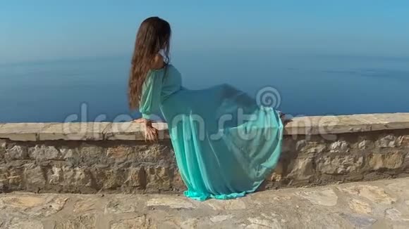 美丽的黑发女孩健康的长发放松在岛上的岩石上的海洋和蓝天斯特凡视频的预览图