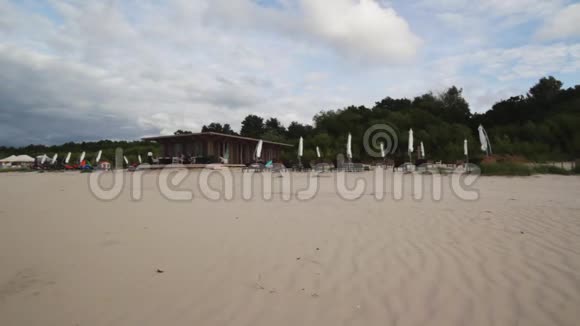阴天有风的小棕现代木制度假村空黄沙滩视频的预览图