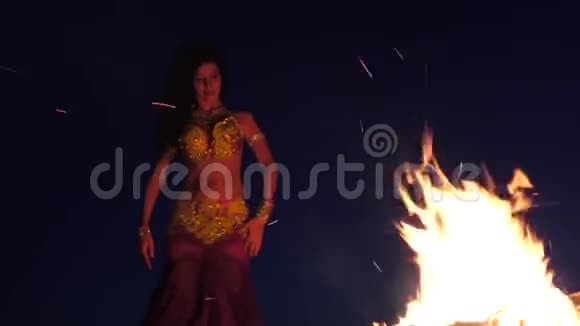 深夜一个在沙滩上跳舞的女孩在明亮的篝火旁跳肚皮舞视频的预览图