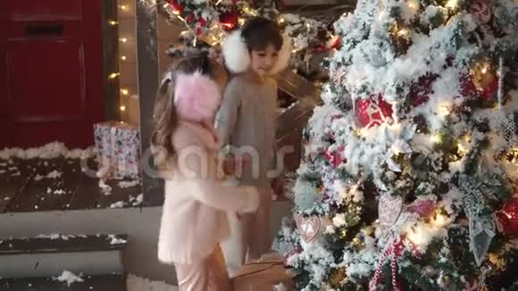 圣诞节或新年两个小妹妹正在看新年树圣诞节背景下的孩子们视频的预览图