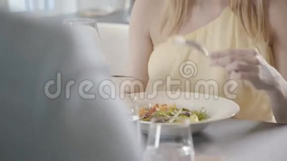一个穿着裙子的温柔的女人正在用叉子和刀子吃沙拉视频的预览图