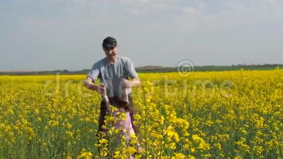 一个男人正在拐一个孩子爸爸把他的女儿变成黄色一个幸福的家庭油菜田视频的预览图