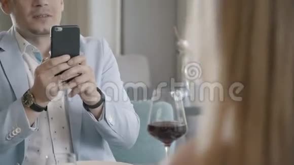 时尚男人在餐馆用智能手机给妻子拍照视频的预览图
