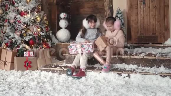 圣诞节或新年孩子们正在看漂亮的圣诞盒子里的礼物两个小女孩在圣诞节视频的预览图