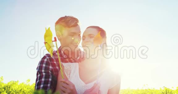 浪漫情侣在芥末场吹着风车视频的预览图