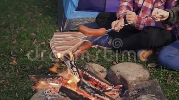 年轻人在火上烤香肠在树林里野餐视频的预览图