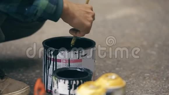 艺术家把黑色的油漆搅拌成一个罐子然后把它倒进另一个罐子视频的预览图
