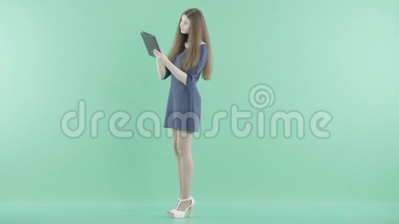 一个微笑的女孩站在那里手里拿着平板电脑视频的预览图
