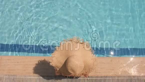一个戴着草帽的女人在蓝色的游泳池里放松俯视图慢动作视频的预览图