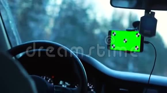 冬天开车的人智能手机有一个绿色屏幕连接在挡风玻璃上视频的预览图