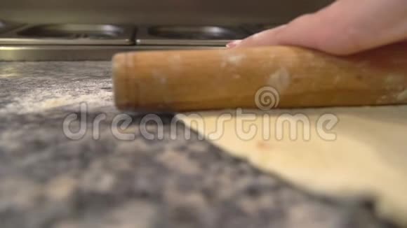 用擀面杖将面团擀成比萨饼金属食品容器位于厨师旁边视频的预览图