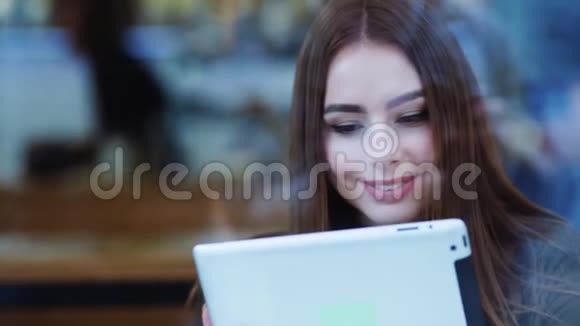 一位年轻貌美的美女坐在一家咖啡馆的窗户旁在网上冲浪视频的预览图