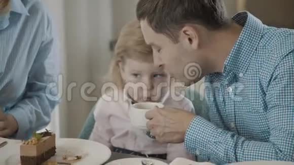 爸爸和女儿一起吹热茶来冷却它家庭视频的预览图