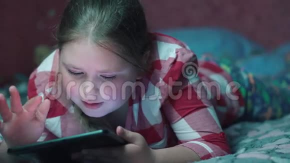 白人女孩在平板电脑上玩游戏晚上躺在沙发上视频的预览图